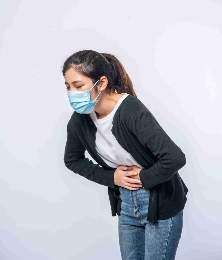 woman standing with stomach ache presses her hand her stomach